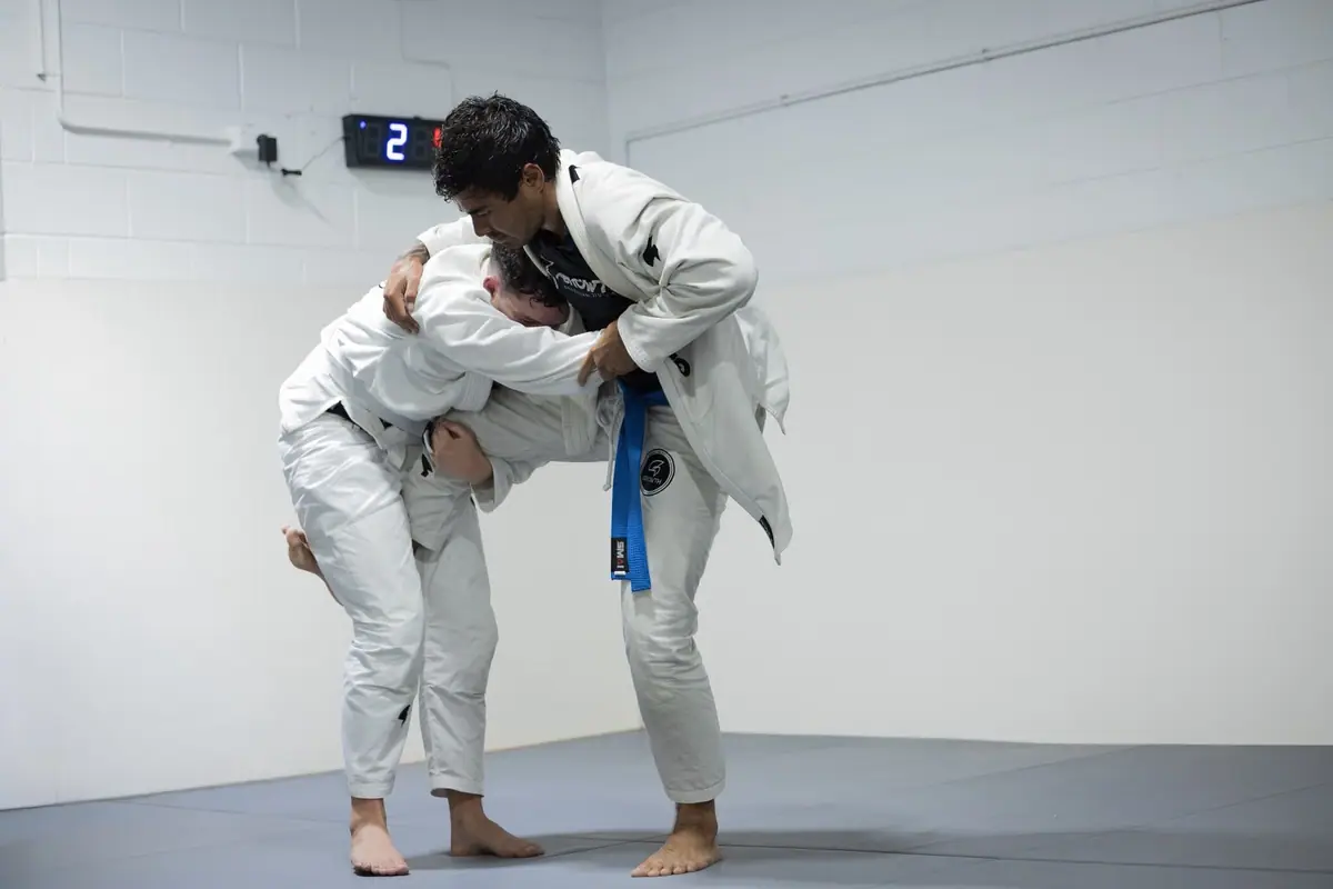 Two students drilling a takedown in the gi