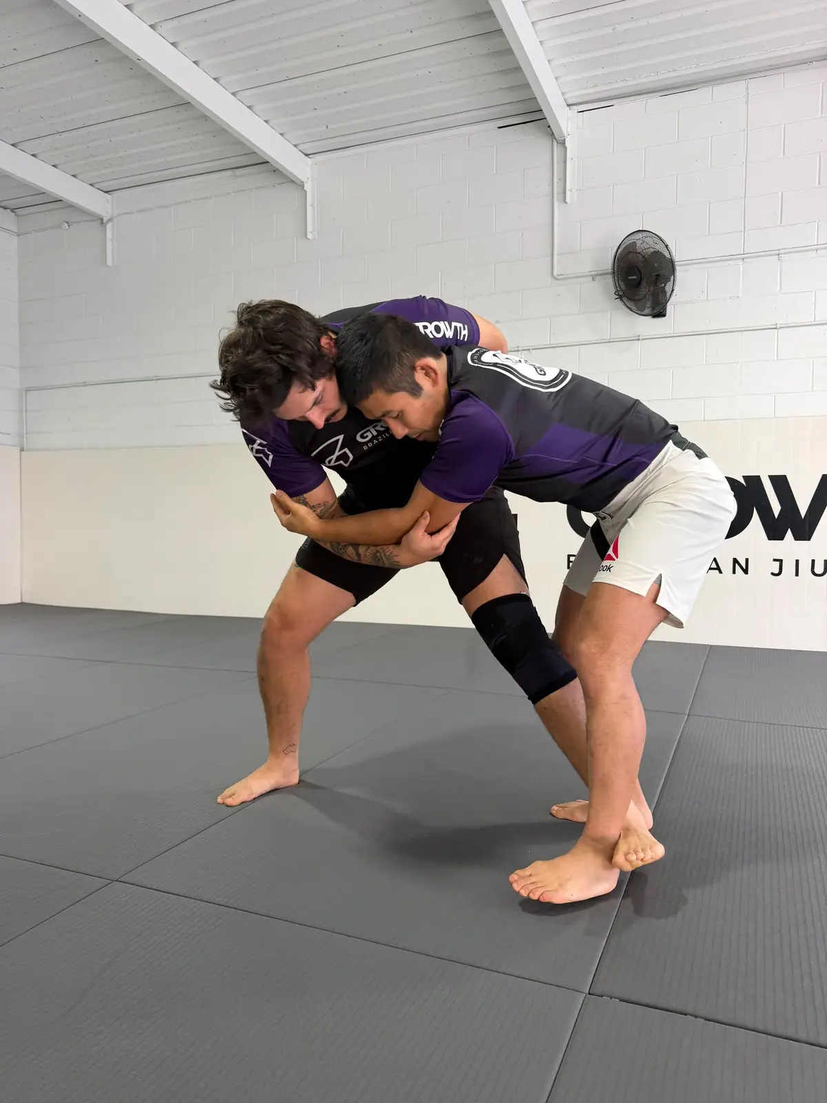 Two adults in Growth rashguards hand fighting in a No-Gi class