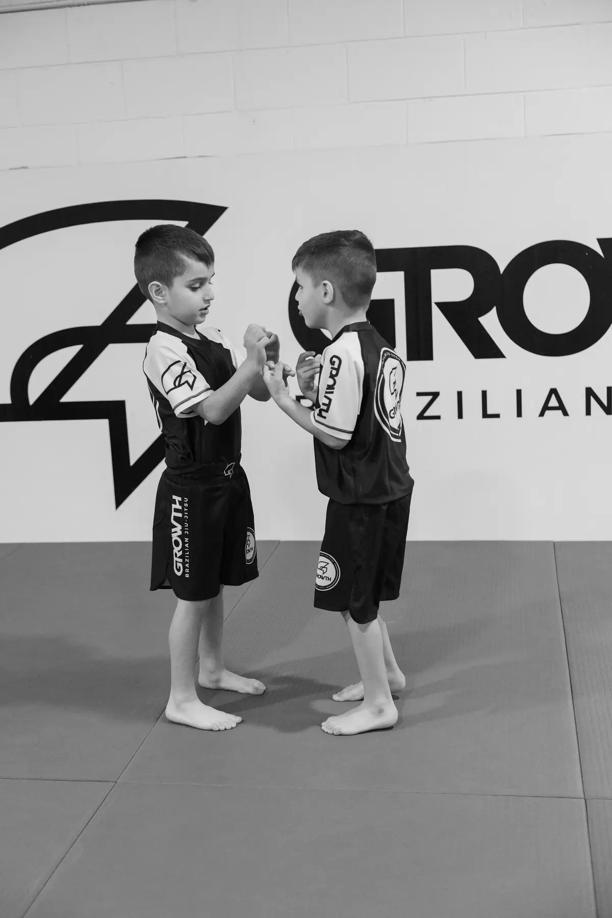 Two boys gripping hands in front of the Growth logo
