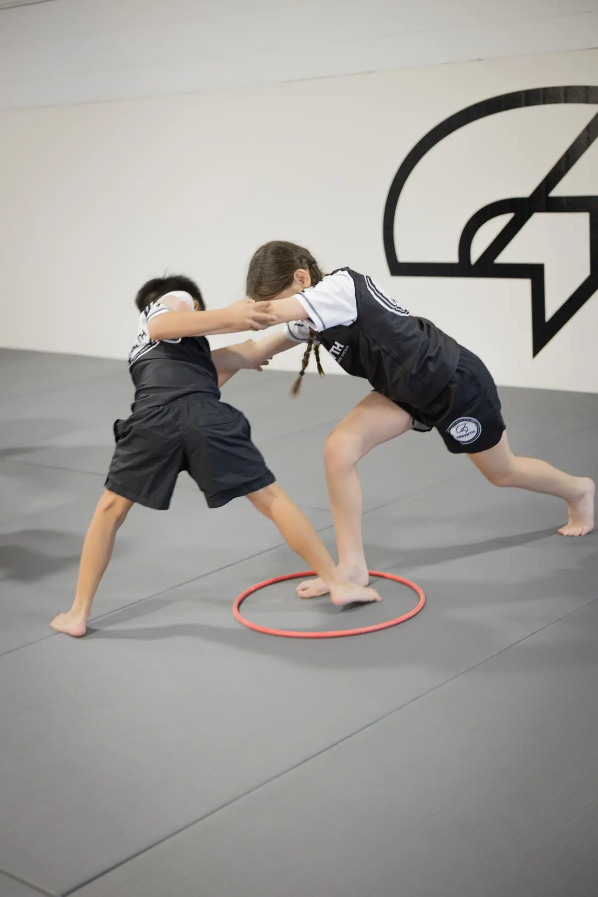 Two kids playing a balance game inside a hoop