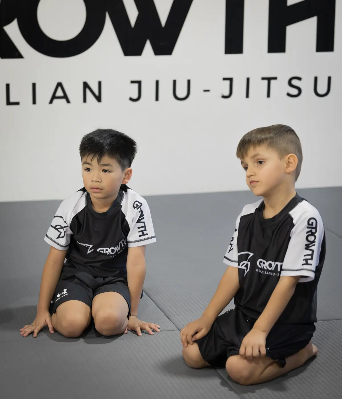 Two kids kneeling on the mat ready to start