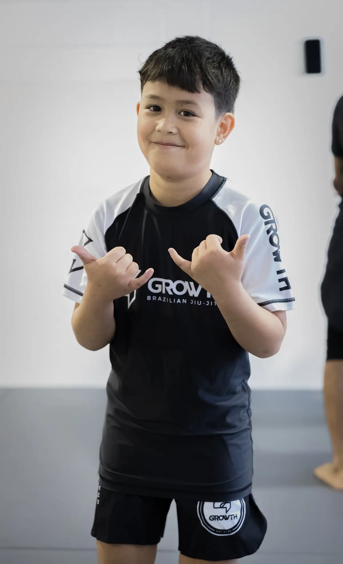 A young student smiling with a shaka in his Growth rashguard