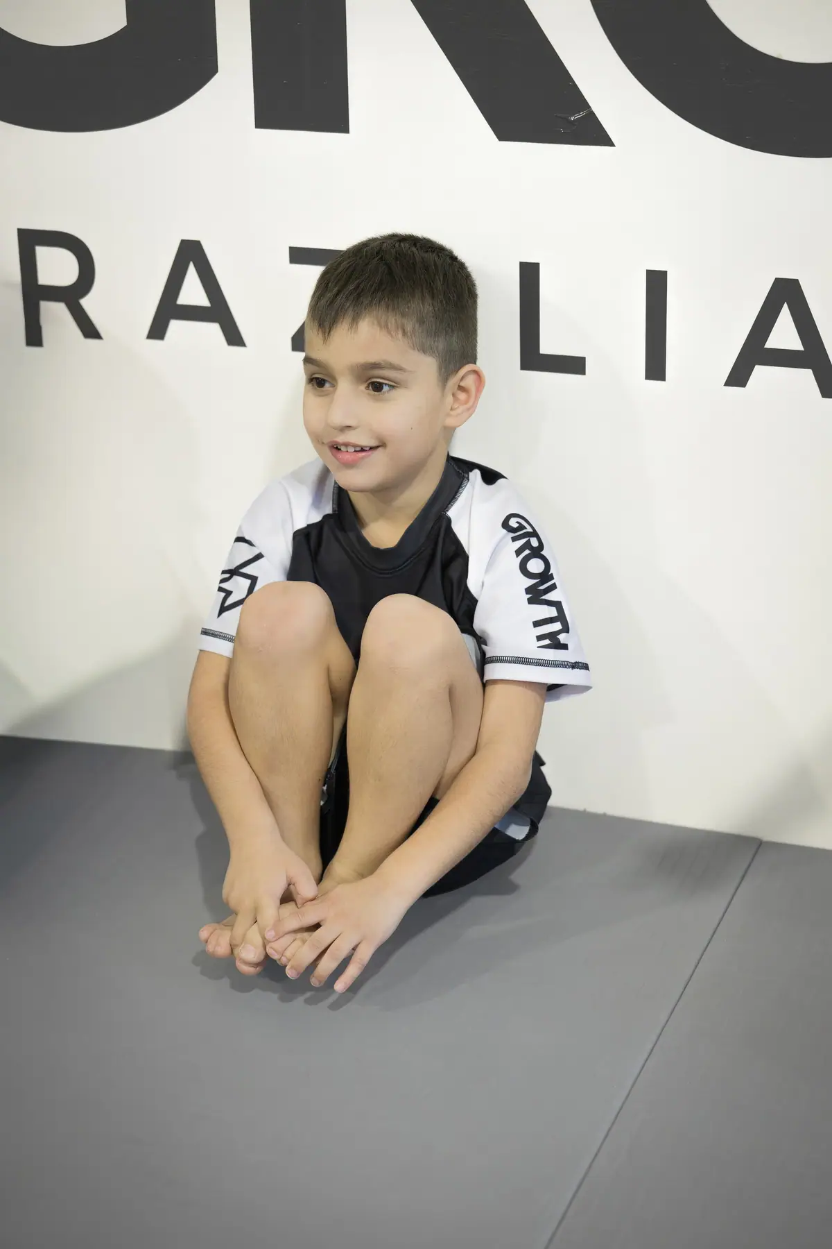 A boy sitting on the mat smiling